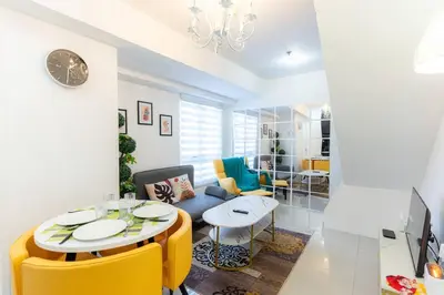 a living room with a table and yellow chairs at A2J Luxury 3BR BGC Loft Near Malls and Airport in Manila