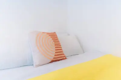 a orange and white pillow sitting on a bed at A2J Luxury 3BR BGC Loft Near Malls and Airport in Manila