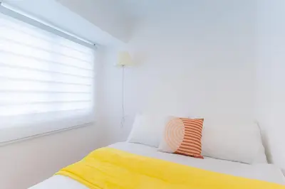 a bedroom with a bed with a yellow blanket and a window at A2J Luxury 3BR BGC Loft Near Malls and Airport in Manila