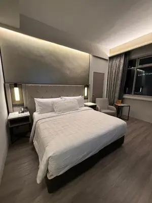 a bedroom with a large white bed and a chair at Condo Unit near MOA, PICC, US Embassy and Airport in Manila