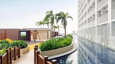 a building with a swimming pool and palm trees at Condo Unit near MOA, PICC, US Embassy and Airport in Manila