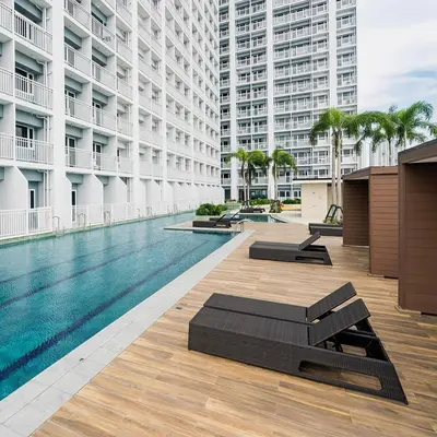 a swimming pool with chaise lounges next to a building at Condo Unit near MOA, PICC, US Embassy and Airport in Manila