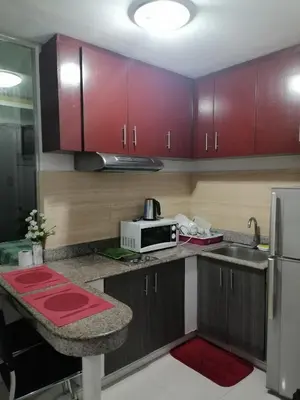 a kitchen with red cabinets and a microwave at Birchtower studio in Manila