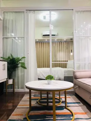 a living room with a coffee table and a bedroom at Urbanview Oasis at Air Residences in Manila