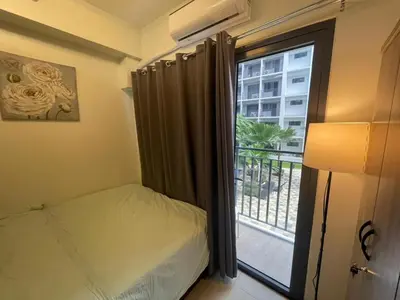 a bedroom with a bed and a window with a balcony at MOA Staycation at Shore 2 in Manila