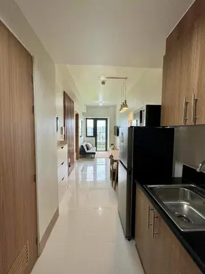 a kitchen with a black refrigerator and a living room at SHORE 3 RESIDENCES TOWER 2 in Manila
