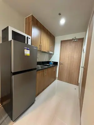 a kitchen with a stainless steel refrigerator and wooden cabinets at SHORE 3 RESIDENCES TOWER 2 in Manila