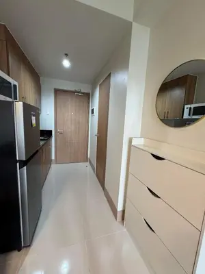 a kitchen with a black refrigerator and wooden cabinets at SHORE 3 RESIDENCES TOWER 2 in Manila