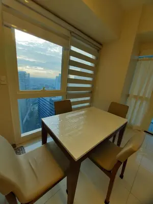a table and chairs in a room with a large window at Bonifacio global city one uptown residence-2 Bedroom in Manila
