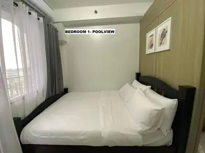 a white bed in a room with a window at Shore Residence D22 shortwalk MOA Balconypoolview in Manila
