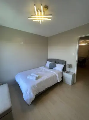 a bedroom with a large white bed and a chandelier at Modern Oasis: Pool + Netflix in Manila