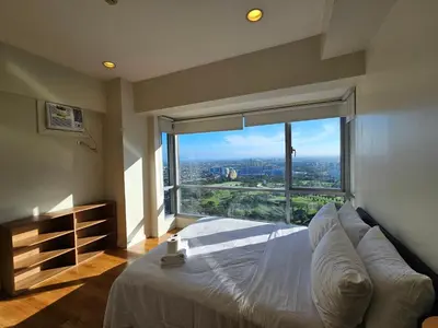 a bedroom with a large bed with a large window at The Infinity Towers in BGC - Simple, Elegant & Spacious 2 Bedroom in Manila