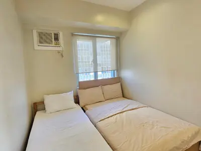 a small room with two beds and a window at The Infinity Towers in BGC - Simple, Elegant & Spacious 2 Bedroom in Manila
