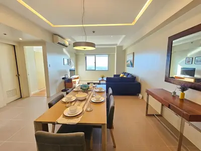 a dining room and living room with a table and chairs at The Infinity Towers in BGC - Simple, Elegant & Spacious 2 Bedroom in Manila
