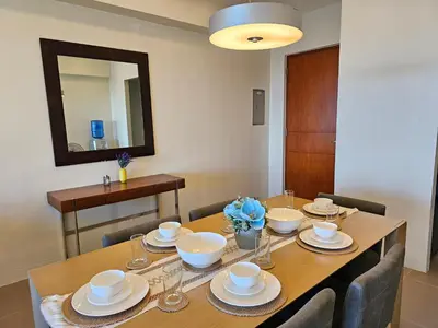 a dining room table with chairs and a mirror at The Infinity Towers in BGC - Simple, Elegant & Spacious 2 Bedroom in Manila