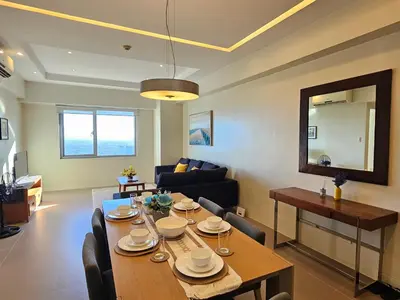 a living room with a table and a dining room at The Infinity Towers in BGC - Simple, Elegant & Spacious 2 Bedroom in Manila