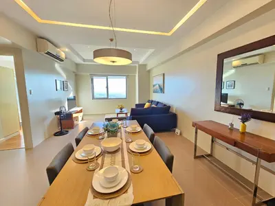 a dining room and living room with a table and chairs at The Infinity Towers in BGC - Simple, Elegant & Spacious 2 Bedroom in Manila