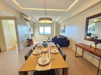 a living room with a wooden table and chairs at The Infinity Towers in BGC - Simple, Elegant & Spacious 2 Bedroom in Manila