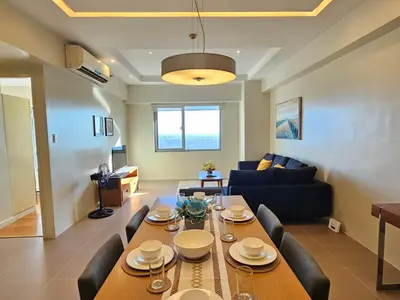 a dining room and living room with a table and chairs at The Infinity Towers in BGC - Simple, Elegant & Spacious 2 Bedroom in Manila