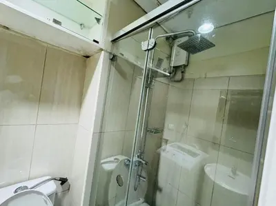 a bathroom with a shower and a toilet and a sink at SHELL RESIDENCE C22 Shortwalk MOA Balcony poolview in Manila