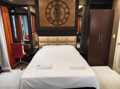 a bedroom with a large bed with a clock on the wall at Modern Condo Infront of NAIA T3 (Virluxe Suites) in Manila