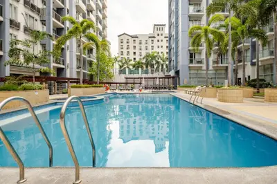 a large swimming pool with palm trees and buildings at Modern Condo Infront of NAIA T3 (Virluxe Suites) in Manila