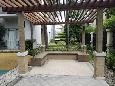 a wooden pergola with a bench in a courtyard at Modern Condo Infront of NAIA T3 (Virluxe Suites) in Manila