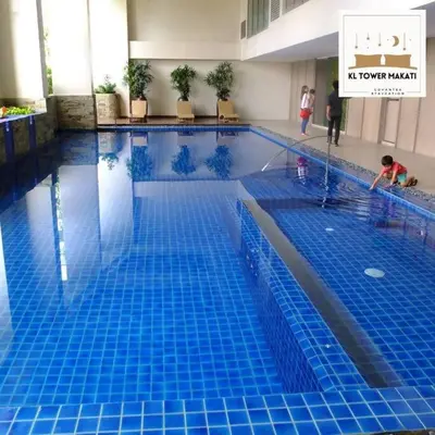 a swimming pool in a hotel with a child playing in it at Muji KLTower Makati - Greenbelt - with Pool Access in Manila