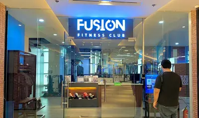 a man walking past a fusion fitness club sign in a store at Frost at Air Residences Makati in Manila
