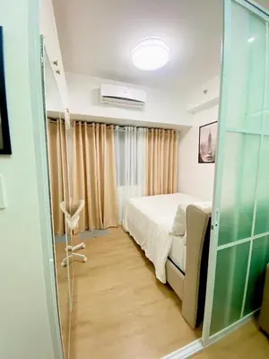 a bedroom with a bed and a glass door at Frost at Air Residences Makati in Manila