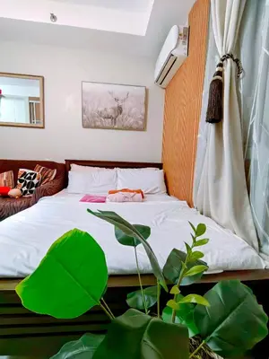 a bedroom with a bed with a plant next to it at CAMP CJ Staycation A Cozy, Modern Studio near BGC & MRT Boni, Perfect for Relaxing City Getaways in Manila