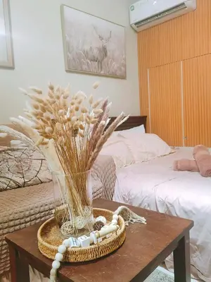 a room with a table with a vase of flowers at CAMP CJ Staycation A Cozy, Modern Studio near BGC & MRT Boni, Perfect for Relaxing City Getaways in Manila