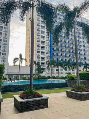 two palm trees in front of a large building at Madison Place at Sea Residences powered by Cocotel in Manila