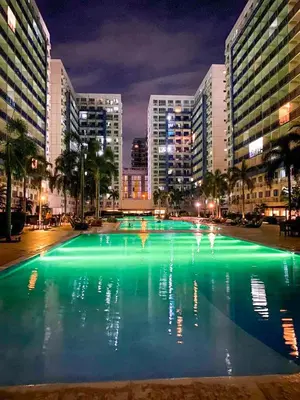 a large pool of green water in a city at night at Madison Place at Sea Residences powered by Cocotel in Manila