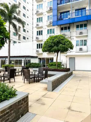 a courtyard with tables and chairs in front of a building at Madison Place at Sea Residences powered by Cocotel in Manila
