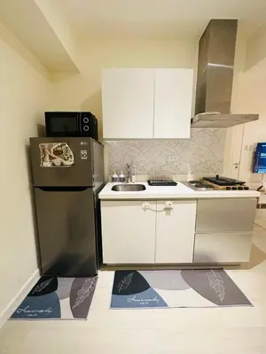 a kitchen with white cabinets and a black refrigerator at Azure Urban Resort Residences Paranaque 2 Bedroom Unit in Manila