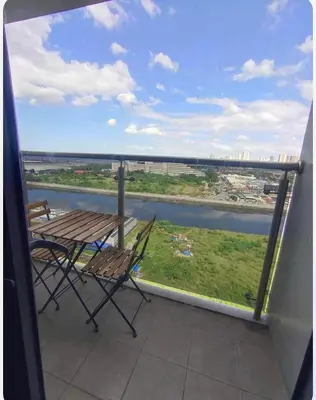 a table and chairs on a balcony with a view of a river at Condotel-Shore 2 Residences MOA in Manila