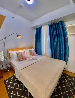 a bedroom with two beds with blue curtains at 8 Adriatico- 1 Bedroom Condo with Balcony in Ermita near US Embassy in Manila