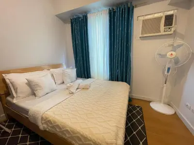 a bedroom with a bed with a fan and a window at 8 Adriatico- 1 Bedroom Condo with Balcony in Ermita near US Embassy in Manila
