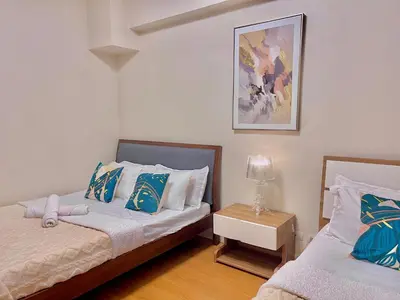 a bedroom with two beds with blue and white pillows at Cozy Staycation Condo for Family in Ermita in Manila