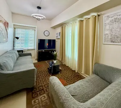 a living room with a couch and a tv at Cozy Staycation Condo for Family in Ermita in Manila