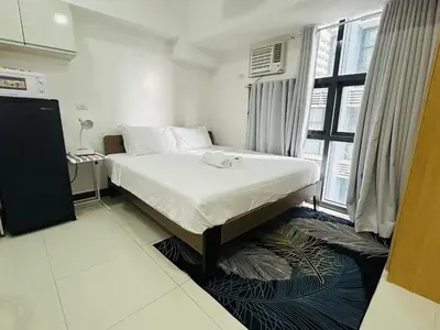 a bedroom with a bed and a large window at 11B Tower 1 Viceroy Residences Mc Kinley Hill BGC in Manila