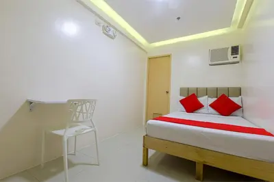 a bedroom with a bed with red pillows and a chair at Freemont Place in Manila