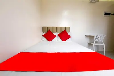 a bed with red pillows in a white room at Freemont Place in Manila