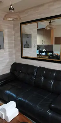 a black leather couch in a living room with a kitchen at SHELL RESIDENCES MOA COMPLEX PASAY in Manila