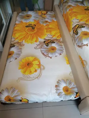 a bed with a floral bedspread with bees on it at SHELL RESIDENCES MOA COMPLEX PASAY in Manila