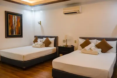 two beds in a room with white walls and wood floors at Teofely Gardens Resort near Tagaytay in Silang