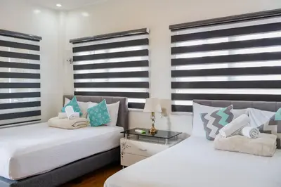 two beds in a room with windowblinds at Teofely Gardens Resort near Tagaytay in Silang
