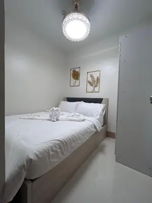 a white bedroom with a large bed with a light at Molly Shore Getaway Unit 1241 in Manila