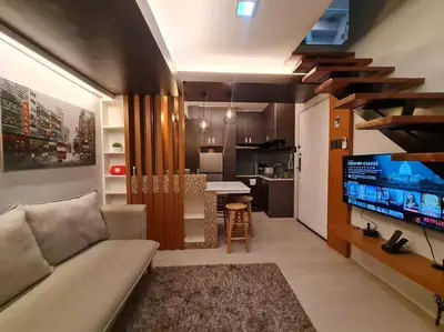 a living room with a couch and a tv and a kitchen at Cozy 2BR in BGC near golf course - B Fort TB in Manila